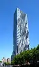 Toren, a high-rise clad in multiple of colors of glass in irregular patterns, viewed from street level