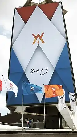 several colourful flags in front of a billboard, all with related designs