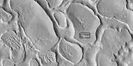 Close view of terrain caused by ice leaving the ground, as seen by HiRISE under HiWish program. Box shows size of football field.
