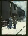 Atchison, Topeka, and Santa Fe railroad conductor George E. Burton and engineer J.W. Edwards comparing time before pulling out of Corwith railroad yard for Chillicothe, Illinois; Chicago. March 1943.