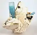 Crystallized white feldspar, with an upright 4&nbsp;cm aquamarine crystal perched on it