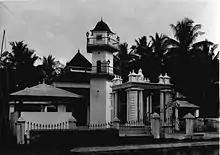 A black and white picture of a mosque with palm trees in the background
