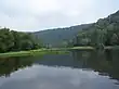 A reservoir surrounded by forested mountain ridges on either side and in the background.
