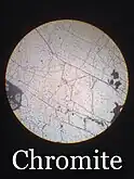 Chromite sample under a petrographic microscope in plain polarized light (PPL)