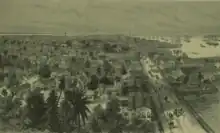 Sketch of Georgetown, Demerera, British Guiana showing the town on the left, people and horses walking on the main waterfront street, and the harbour on the right, filled with ships