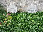 Two graves and two gravestones side by side; heading behind a bed of green leaves, bearing the remains of Vincent and Theo van Gogh, where they lie in the cemetery of Auvers-sur-Oise. The stone to the left bears the inscription: Ici Repose Vincent van Gogh (1853–1890) and the stone to the right reads: Ici Repose Theodore van Gogh (1857–1891)