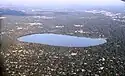 An aerial view of Lake Harriet surrounded by parkland and mostly low residential buildings