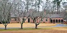 A brick home with brown trim and a large lawn in front.