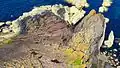 The rugged point, seen from above, shows gently sloping beds of red sandstone above vertical beds of greywacke, forming a classic example of Hutton's Unconformity.