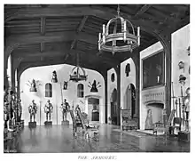Suits of armor arranged in a large room with a fireplace