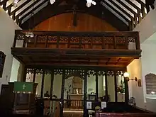 View of the carved wooden balcony and rood screen. The pulpit is visible and the chancel is in the background.