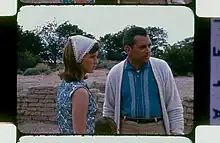 A woman and a man looking right, the head of a child is at the bottom of the image, this is not visible in the preceding image