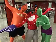 People in coloured zentai suits with text and logos