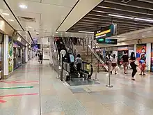 View of the NEL platforms with an escalator going upwards. Two prints are on the opposite sides of the platform, on the pillars in between the platform screen doors.