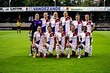 Eleven women in football kit posing for a group photo