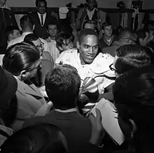 Simpson surrounded by reporters, smiling