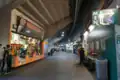 A shot of the concourse showing a vendor of A's merchandise, a bathroom sign, and entrances to the stadium seating
