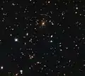 Jellyfish galaxy in SDSS J1110+6459, visible next to the cluster and apparently dripping bright blue material.