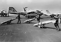 An A-6E TRAM Intruder (NF-506) from VA-115 and an F/A-18A Hornet (NF-106) from VFA-195 taxi to a catapult during the Gulf War.