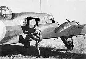 Rear three-quarter view of twin-engined military aircraft, being boarded by a man in flying gear