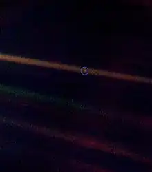 A tiny, pale blue dot is contrasted against the vastness of space