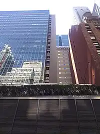 The facade as seen from 54th Street. Most of the facade is made of green glass, but there is a masonry "spine" visible at center right.