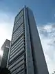 Ground-level view of a 40-storey, box-like building with windowless concrete siding and rounded anterior corners
