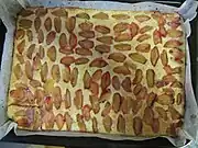 Sheet pan with sliced plums laid across the cake batter
