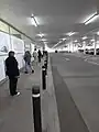 People queueing at an Irish supermarket, March 2020; strips of black tape on the ground to demarcate 2-metre gaps.