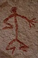 Humanoid stick figure painted on a rock wall in red. The figure is shown in Stylistic group C.