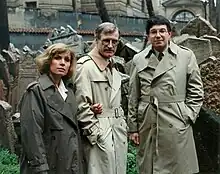 Two men and a woman standing in front of grave stones