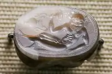 Engraved gem of a reclining satyr, Etruscan c. 550 BC, 2.2&nbsp;cm wide. Note the vase shown "sideways"; it is characteristic of early gems that not all elements in the design are read from the same direction of view.