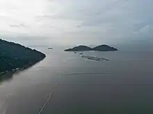 A patch of land being reclaimed from the sea, with an island visible in the background.