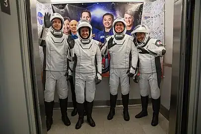 Photo of Crew-2 astronauts waving from an elevator of the Neil Armstrong Operations and Checkout Building