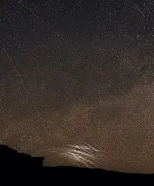 Starlink satellites repeatedly flaring low over horizon.