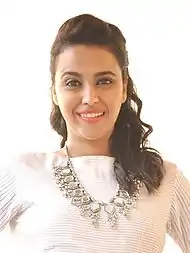 Bhaskar, in a white dress smiling at the camera.