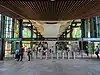 Picture of Rouse Hill station. The station has elevated platforms. The picture was taken below the platforms at the ground level concourse, which is surrounded by green-coloured glass on the exterior.
