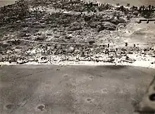 Aerial view of Betio Island, 24 November 1943, looking north toward "The Pocket", the last place of Japanese resistance. An emplacement just onshore with two 12.7&nbsp;mm anti-aircraft guns is visible near the left edge of the photograph.