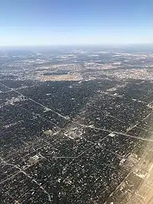 The path of tornado damage across North Dallas from the air the following morning. Looking southwest, the Dallas North Tollway is visible across the middle, and Dallas Love Field Airport is in the distance. The tornado travelled from top-right to bottom-left in this photo.