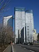 Ground-level view of a three-building complex; each building is white and blue and lined with rows of windows