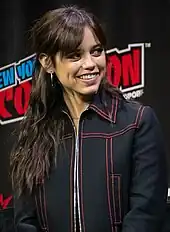 Ortega, wearing a black jacket, smiling towards her left