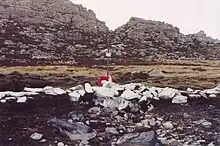 A cross amongst rocks painted white and a mountain in the background