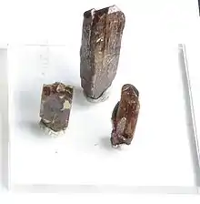 Three column shaped brown crystals on a white background